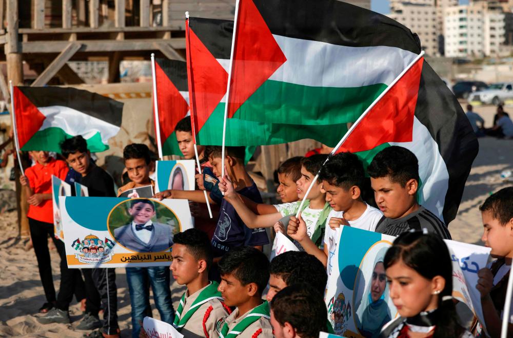 Scouts carrying Palestinian flags and pictures of children who were killed during the latest round of conflict between Israel and Palestinian militants, gather along the coast of Gaza City during a commemorative event, on August 17, 2022. AFPPIX
