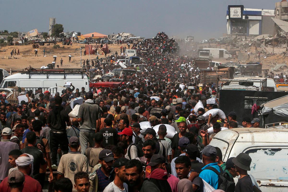Displaced Palestinians carry food parcels as they raid trucks carrying humanitarian aid in Khan Yunis, in the southern Gaza Strip on August 9, 2025. Nearly two years into the war in Gaza, Israel’s Prime Minister Benjamin Netanyahu faces mounting pressure to secure a truce to pull the territory’s more than two million people back from the brink of famine and free the hostages held by Palestinian militants. - AFPpix