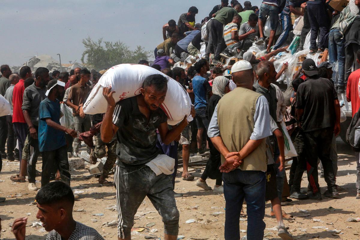 A man carries a bag of food as displaced Palestinians raid trucks carrying humanitarian aid in Khan Yunis, in the southern Gaza Strip on August 9, 2025. - AFPpix