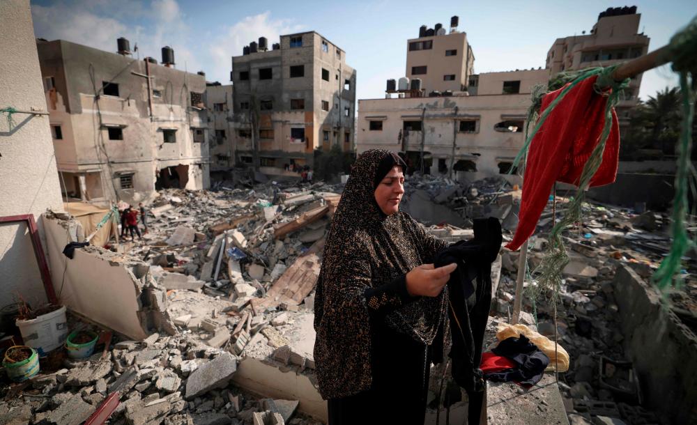 A Palestinian woman hangs clothes she picked from the rubble on August 8, 2022 outside her home. AFPPIX