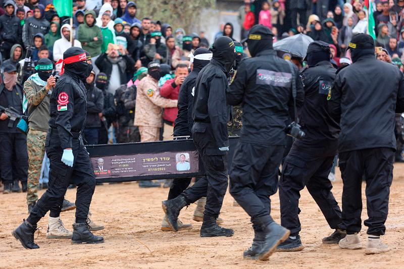 Armed Palestinian militants carry one of the four coffins during the hand over of the bodies of four Israeli hostages to the Red Cross in Khan Yunis in the southern Gaza on February 20, 2025. Hamas handed over on February 20 coffins believed to contain the bodies of four Israeli hostages, including those of the Bibas family who became symbols of the ordeal that has gripped Israel since the Gaza war began. The transfer of the bodies is the first by Hamas since its October 7, 2023 attack on Israel triggered the war, and is taking place under a fragile ceasefire that has seen living hostages exchanged for Palestinians held in Israeli prisons. - Omar AL-QATTAA / AFP