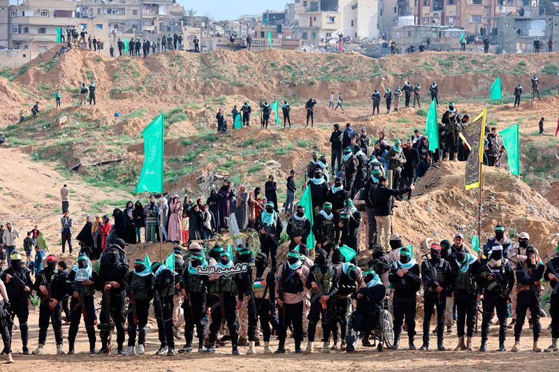 Palestinian Hamas militants and people gather at the site of the handing over of the bodies of four Israeli hostages in Khan Yunis in the southern Gaza on February 20, 2025. Hamas handed over the bodies of four hostages on February 20, including those of the Bibas family, who have become symbols of the hostage crisis that has gripped Israel since the Gaza war broke out. The transfer of the bodies is the first such handover of remains by Hamas since its October 7, 2023 attack on Israel triggered the war. - Omar AL-QATTAA / AFP