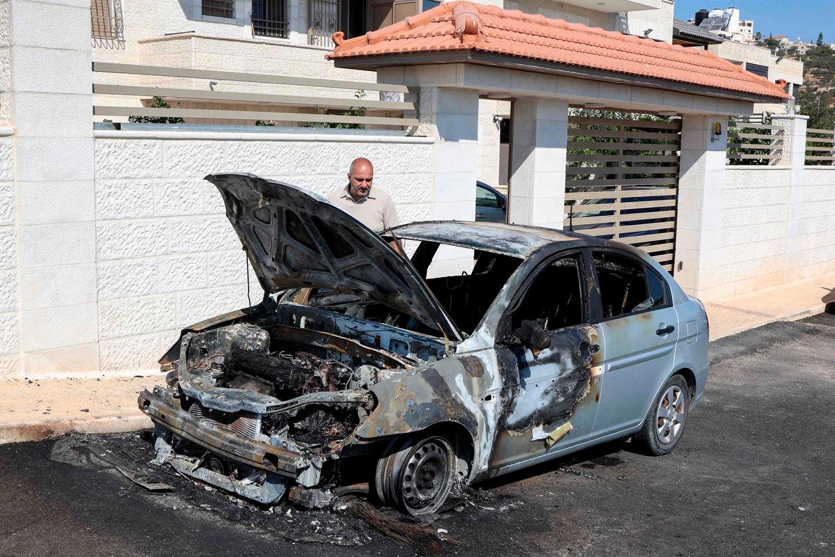 A man inspects a vehicle that was reportedly torched by Israeli settlers during an overnight attack on the Palestinian Christian village of Taybeh, northeast of Ramallah in the occupied West Bank, on July 28, 2025. (Photo by Zain JAAFAR / AFP)