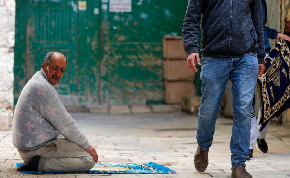 A Palestinian man prays outside the closed al-Aqsa mosque compound in Jerusalem's Old City, amid measures to stem the spread of the novel coronavirus, on March 27, 2020. - AFP