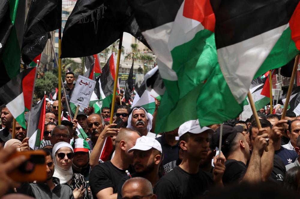 Warga Palestin mengibarkan bendera kebangsaan ketika mereka berarak dalam perhimpunan menandakan ulang tahun ke-74 “Nakba” atau “malapetaka”, di bandar Ramallah, Tebing Barat yang diduduki, pada 15 Mei 2022.