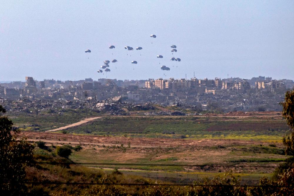 A general view taken from the Israeli side of the border shows aid parcels being airdropped over the northern Gaza Strip on March 5, 2024/AFPPix