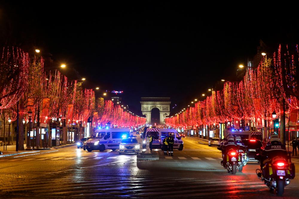 Policemen patrol on the Champs Elysees avenue during New Year's Eve as a 8:00pm-6:00am curfew is implemented in France to avoid a third wave of Covid-19 infections, in Paris, on December 31, 2020. — AFP