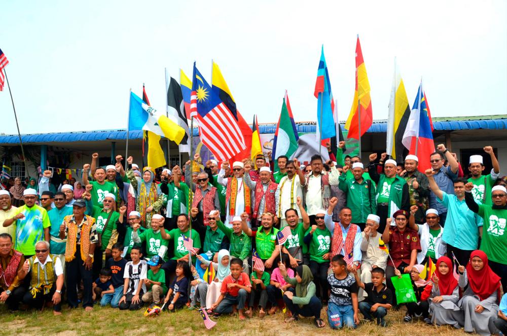 Abdul Hadi (centre, in white) and PAS leaders join Rumah Gima residents in shouting ‘Happy Malaysia Day’ during a photo-call in front of the longhouse. — TheBorneoPost