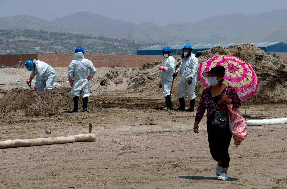 A woman walks by as cleaning crews work to remove oil from a beach in the Peruvian province of Callao on January 17, 2022, after a spill which occurred during the unloading process of the Italian-flagged tanker “Mare Doricum” at La Pampilla refinery caused by the abnormal waves recorded after the volcanic eruption in Tonga. AFPPIX