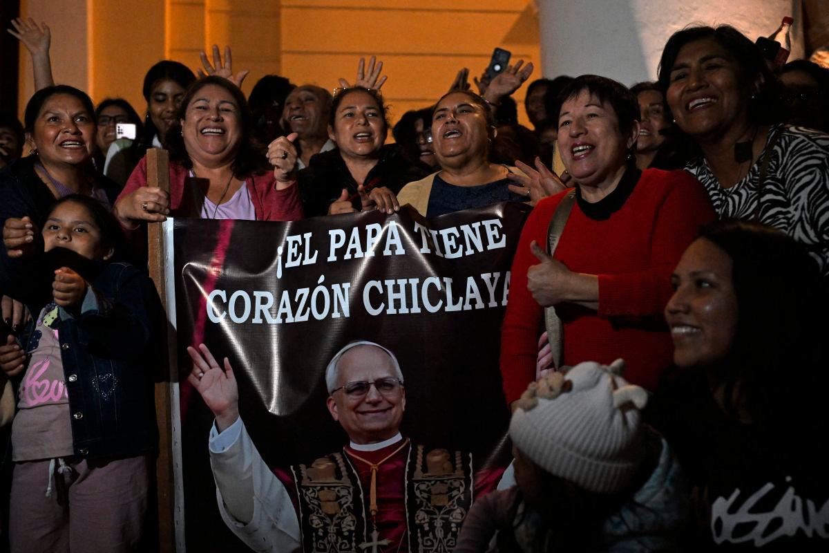 People pose next to the image of Robert Francis Prevost, who became Pope Leo XIV on May 8, 2025.AFPpix