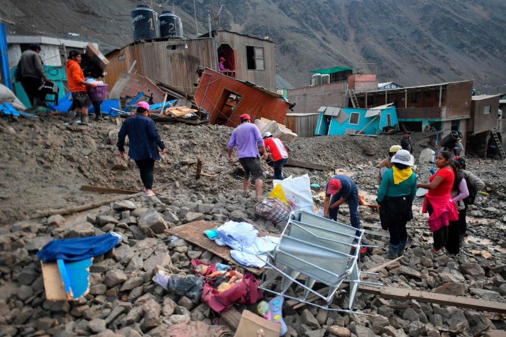 Residents of the isolated village of Camana, 840 kilometers south of Lima, walk among the debris left after a landslide in Peru on February 6, 2023/AFPPix