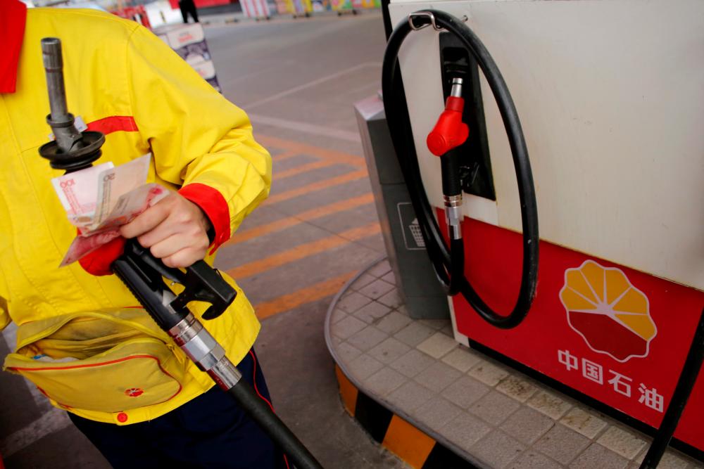 An attendant pumps fuel into a customer's car at a PetroChina petrol station in Beijing. – REUTERSPIX