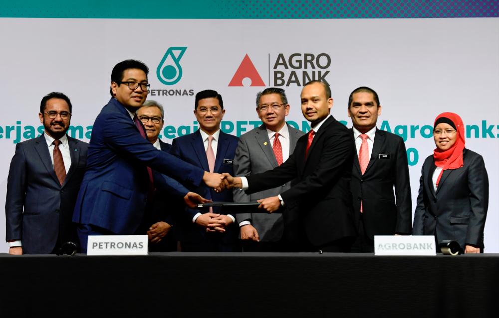 Petronas executive vice-president and chief financial officer Tengku Muhammad Taufik Tengku Aziz (second from left) and Agrobank chief business officer Ahmad Shahril Mohd Sharif exchange documents at the signing ceremony today. Looking on are, from left, Petronas president and group CEO Tan Sri Wan Zulkiflee Wan Ariffin, Petronas chairman Datuk Ahmad Nizam Salleh, Economic Affairs Minister Datuk Seri Mohamed Azmin Ali, Agriculture and Agro-Based Industry Minister Datuk Seri Salahuddin Ayub,
