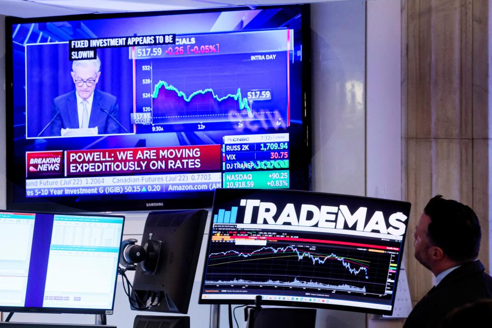 Traders work as Powell is seen delivering remarks on a screen on the floor of the New York Stock Exchange yesterday. – Reuterspix