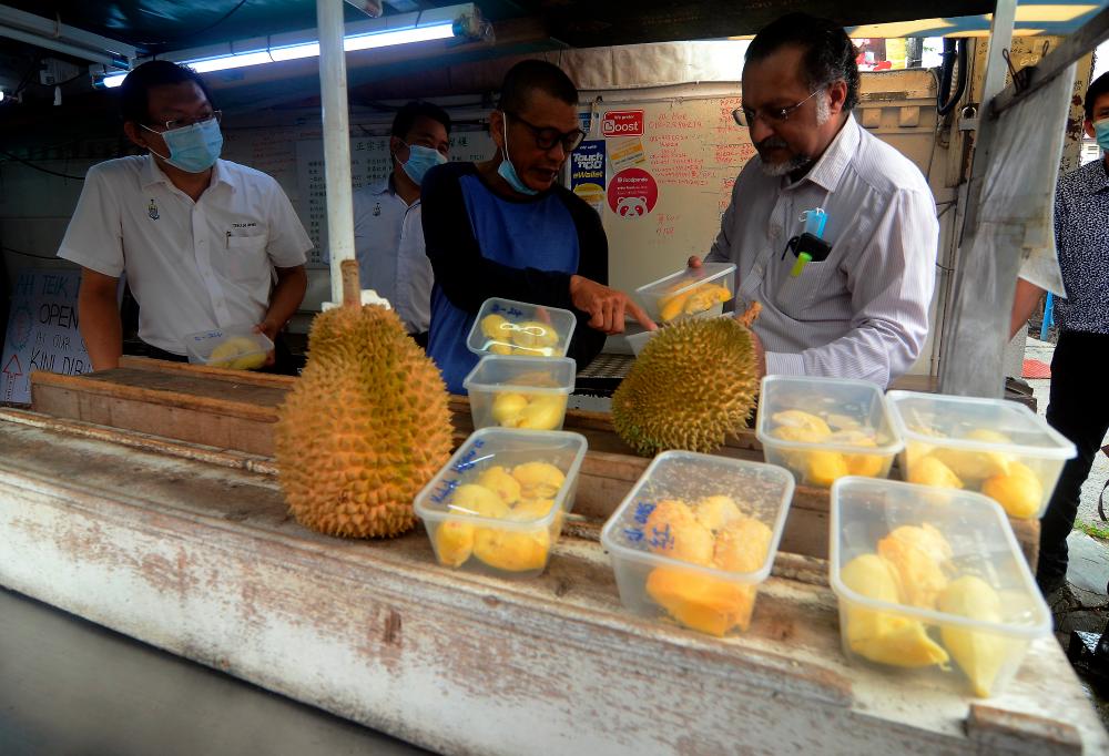 Penang State Housing, Local Government and Town and Country Planning Committee chairman Jagdeep Singh Deo (R) observes a durian stall along Lorong Susu today. - Bernama