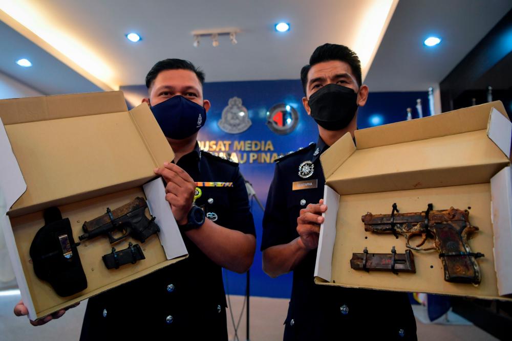 Pegawai Penyiasat Jabatan Siasatan Jenayah (JSJ) negeri ASP Mustapha Maidin (kanan) dan ASP Azuary Norazmi menunjukkan dua pucuk pistol semi auto jenis Glock dan Beretta serta 90 butir peluru hidup 9mm yang dirampas di kawasan kebun buah-buahan dekat Teluk Bahang pada 26 Mei lepas ketika sidang media oleh Ketua Polis Pulau Pinang Datuk Mohd Shuhaily Mohd Zain di Ibu Pejabat Polis Kontinjen Negeri hari ini. fotoBERNAMA
