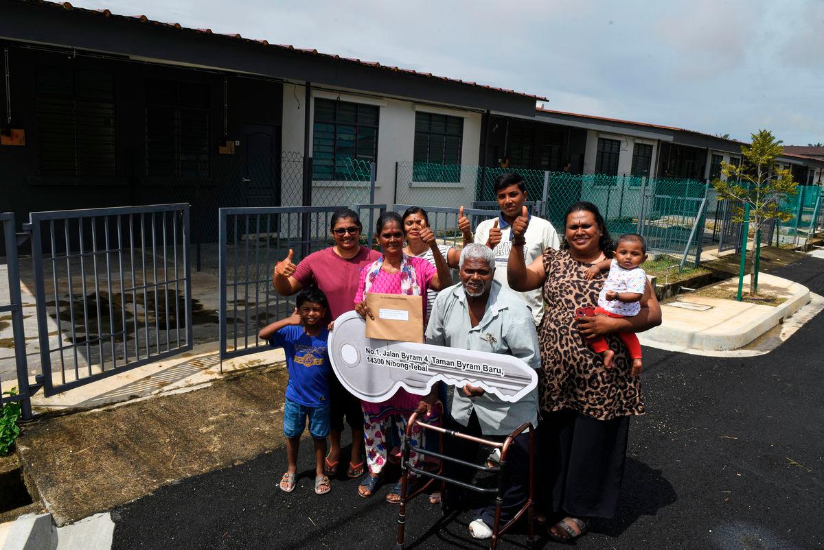 T. Kuppusamy, 73, (dua dari kanan) bersama isterinya, S. Malliga, 61, (dua dari kiri) serta ahli keluarga bergambar di hadapan rumah baharu mereka pada Majlis Perasmian Projek Penempatan Semula Penduduk Ladang Byram ke tapak baharu di Jalan Sungai Daun, Mukim II, Nibong Tebal, hari ini. - BERNAMA