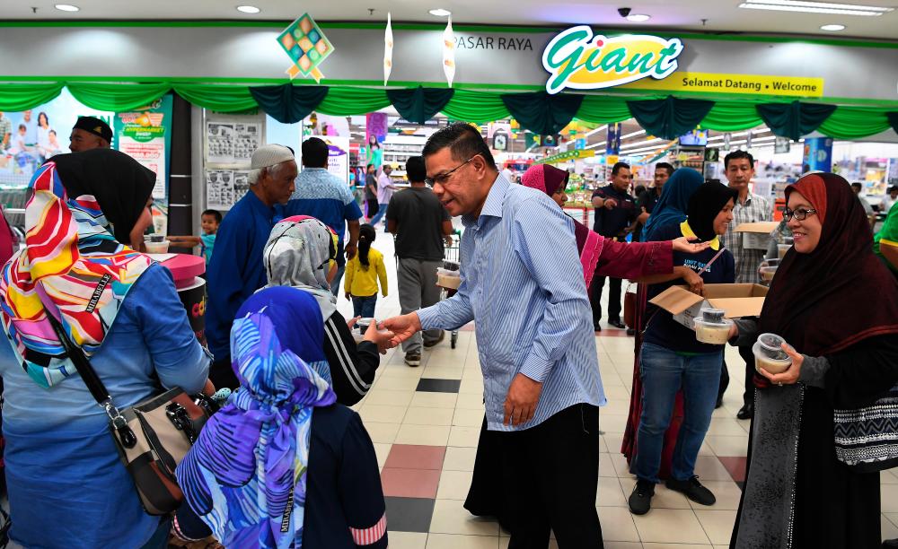 Domestic Trade and Consumer Affairs Minister Datuk Seri Saifuddin Nasution Ismail distributes bubur lambuk and dates to the public at the Bayan Baru Giant Supermarket, George Town on May 25, 2019. - Bernama
