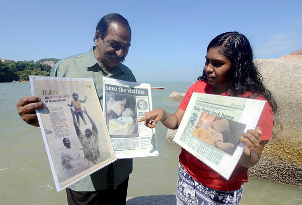 A. Suppiah, 70 shows news pages about his daughter S. Thulasi, 15 (right) the Tsunami’s miracle baby, at Batu Ferringhi today. — Bernama