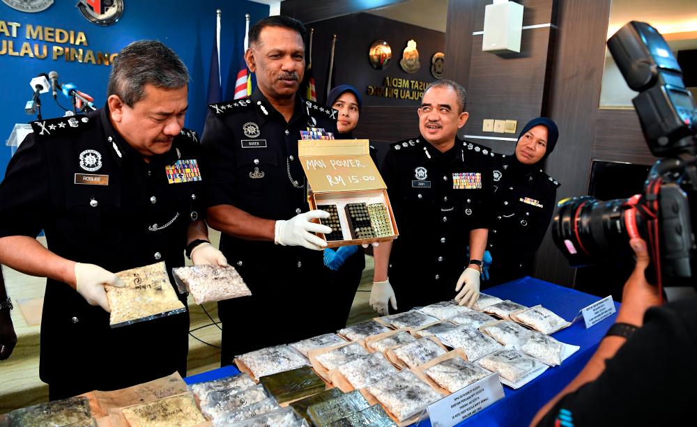 Penang police chief Datuk T. Narenasagaran (2nd from L) along with his officers display the ammunition and drugs seized after a raid on a drug-processing syndicate, during a press conference at the Penang police headquarters in George Town today. - Bernama
