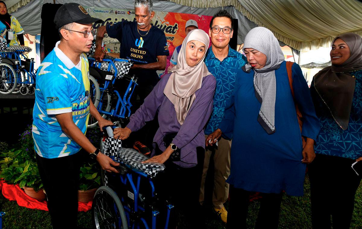 The Deputy Chief Minister I of Penang, Datuk Dr Mohamad Abdul Hamid (left), presented a wheelchair to Nur Hasliza Abdullah, 29, at the “People’s Carnival with Deputy Chief Minister I: Takaful Goes to the Village” tour stop held at Sungai Ara Secondary School today. Also present was the Chief Executive Officer of the Malaysian Takaful Association (MTA), Mohd Radzuan Mohamed (third from right). - BERNAMA