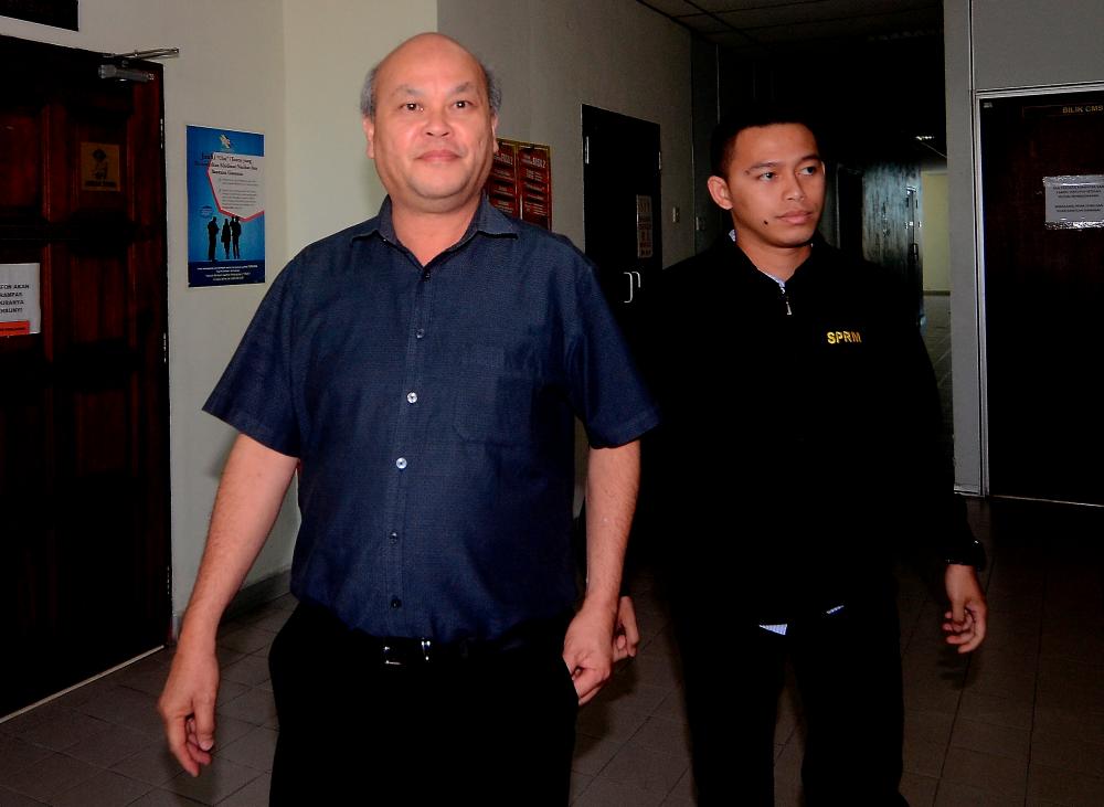 Ex-headmaster of Sekolah Kebangsaan (SK) Wellesley in George Town, Chan Thye Choon, 61, (L) is accompanied by an officer of the MACC to the special court of corruption in Butterworth today on eight charges of CBT. - Bernama