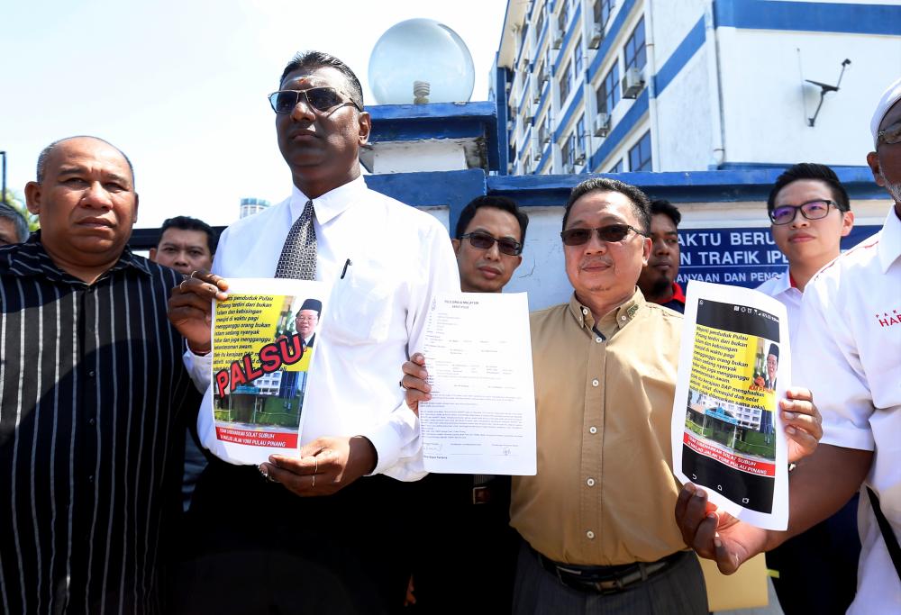 Jelutong MP RSN Rayer (2nd from L) and information officer in the Penang Chief Minister’s Office Zahar Zainul (2nd from R) display a police report on the spread of defamatory statements linking Penang Chief Minister Chow Kon Yeow with the administration of Islamic affairs and mosque administration in the state at the Northeast district police headquarters today. - Bernama