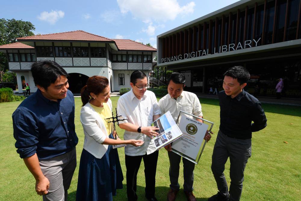 Principal architect of the Penang Digital Library project, Tan Bee Eu (2nd from L), shows off the Penang Digital Library (PDL) structure book to Finance Minister Lim Guan Eng (C) today. - Bernama