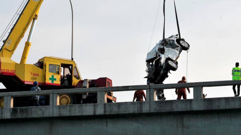 Filepix taken on Jan 20 shows rescue workers recovering the SUV after it veered off the Penang Bridge. — Bernama