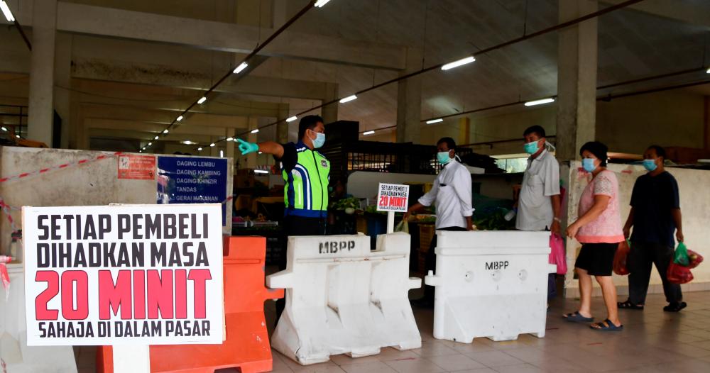Enforcement officers from the Penang Island City Council (MBPP) ensure social distancing SOP for Covid-19 are practised, at the Balik Pulau wet market, on April 3, 2020. — Bernama