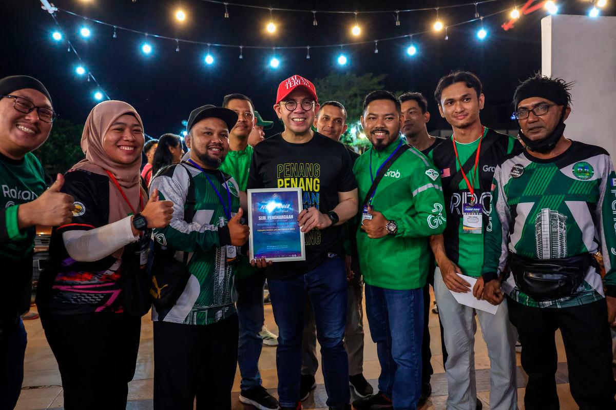 Human Resources Minister Steven Sim Chee Keong poses with gig workers during the Penang Rider Jalan Teruih Program at Healing Sampai Pagi last night (21 Sept). - BERNAMA