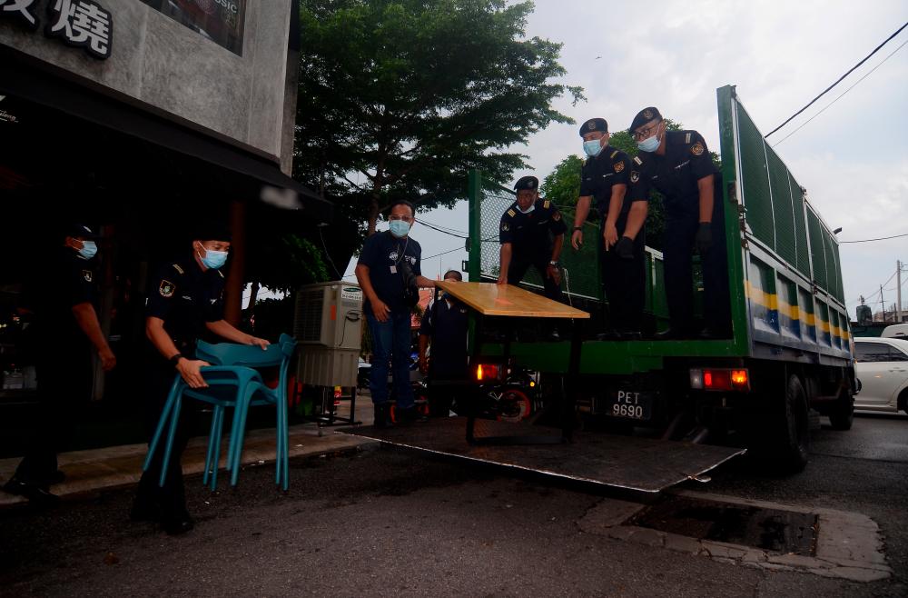 Enforcement officers from the Seberang Perai City Council (MBSP) confiscate tables and chairs from a restaurant in Jalan Kampung Paya, Raja Uda for violating the standard operating procedures (SOPs) during the Conditional Movement Control Order (CMCO), on May 31, 2020. — Bernama