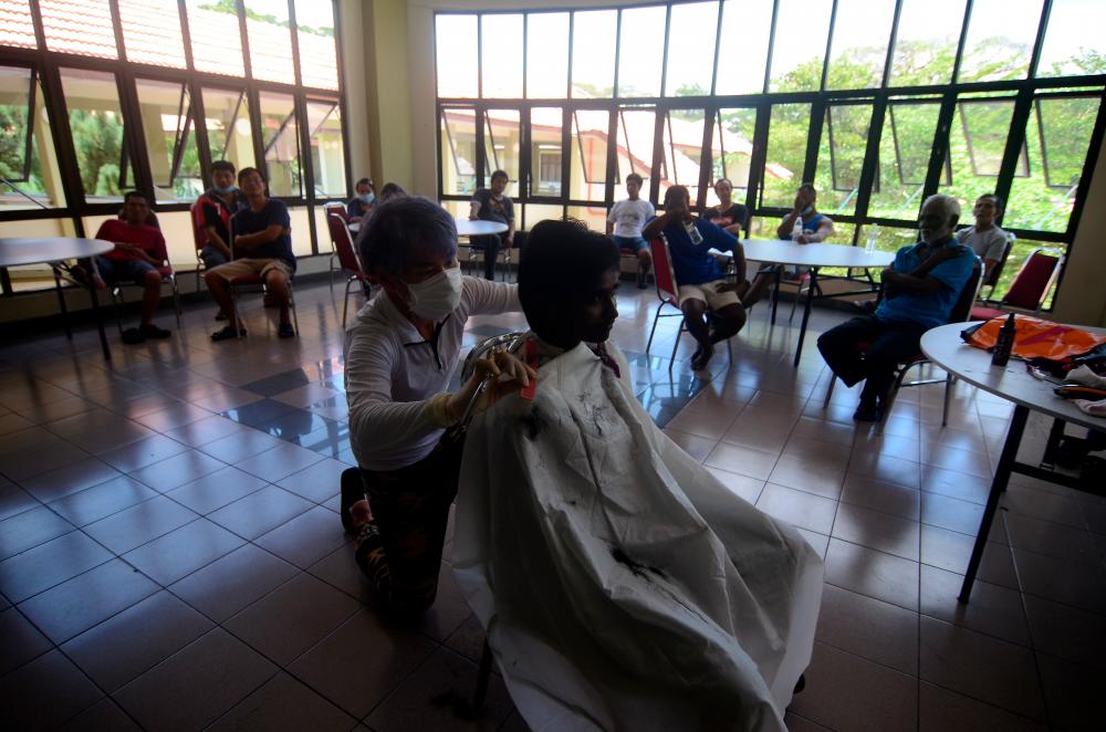 Calvin Ch’ng Soon Kok gives a haircut to one of his homeless clients who has now been temporarily placed at the Kompleks Masyarakat Penyayang, on April 6, 2020. — Bernama