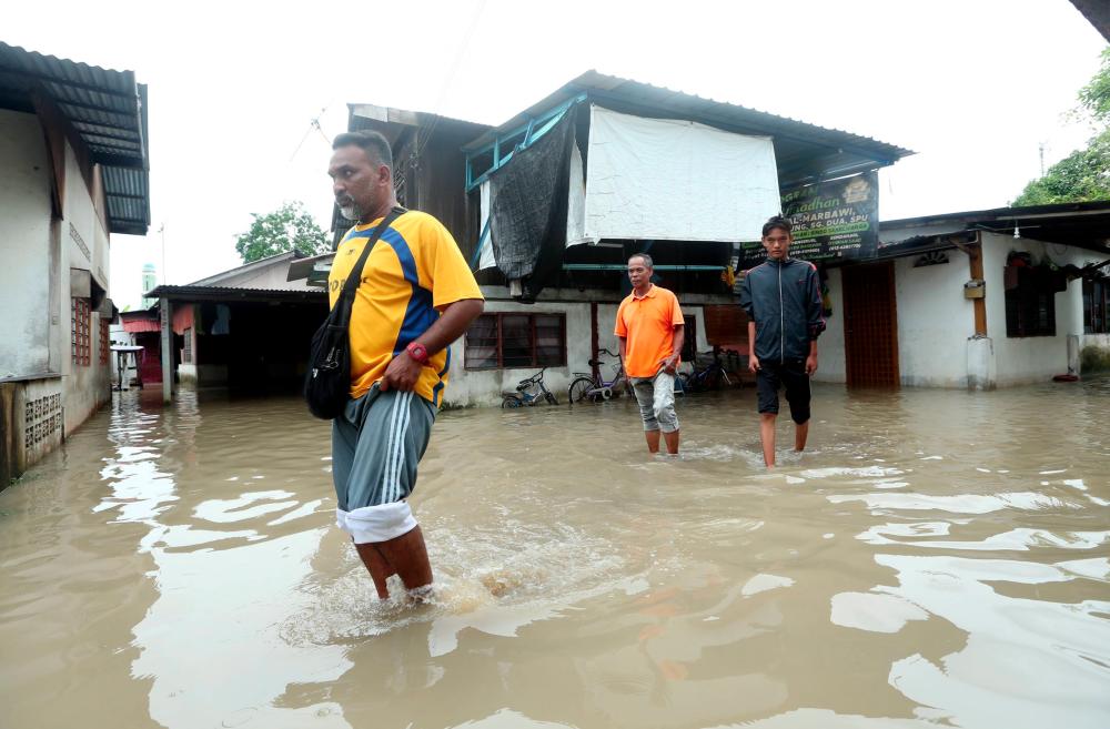 Penduduk Residents of Kampung Merbau Kudung wade through floodwater in Tasek Gelugor on May 9, 2019. — BBX