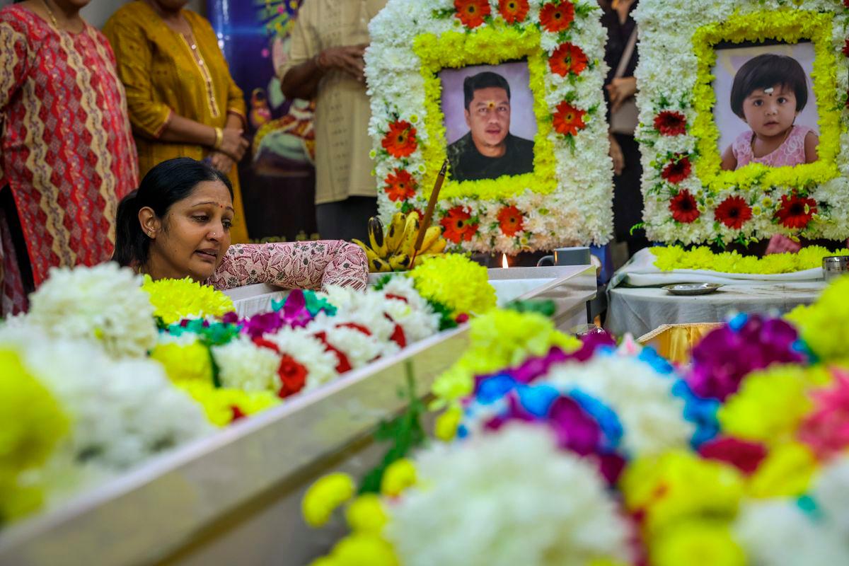 S. Sanggetha, 39, (left) pays her last respects to her late husband S. Arumugam, 40, and their daughter A. Sarrvihka, 3, at their home near Taman Bayu Aman today. Photo by BERNAMA