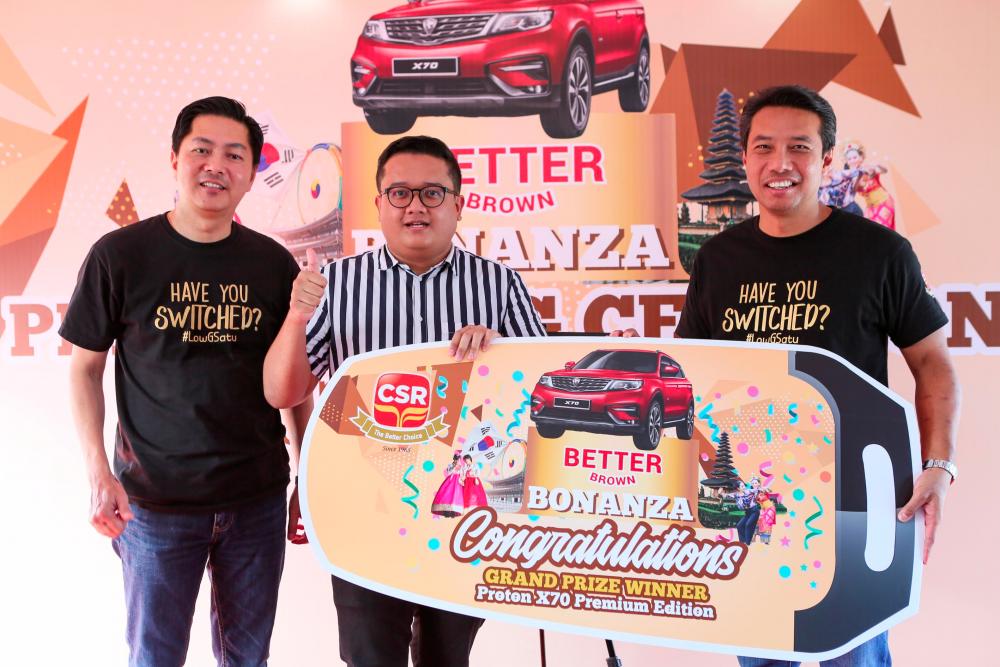 From left: CSR sales director Henry Ong with Muhammad Falihin who received the mock car key for the Proton X70 SUV grand prize from Hishammudin.