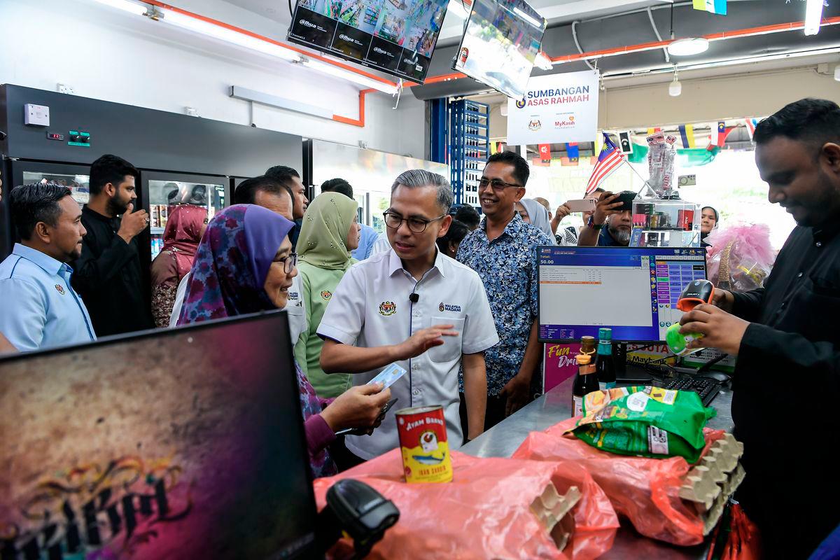 Communications Minister Datuk Fahmi Fadzil mingled with some recipients during an inspection of the Sumbangan Asas Rahmah (SARA) initiative in Kubang Semang here today. – BERNAMA