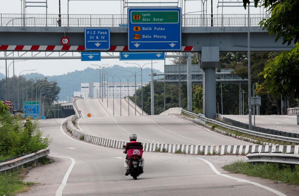 $!LONE RIDER ... A single motorcyclist seen on a usually busy road near Queensbay Mall in Penang yesterday as people stay home to observe an enhanced movement control order in the state. – MASRY CHE ANI/THESUN