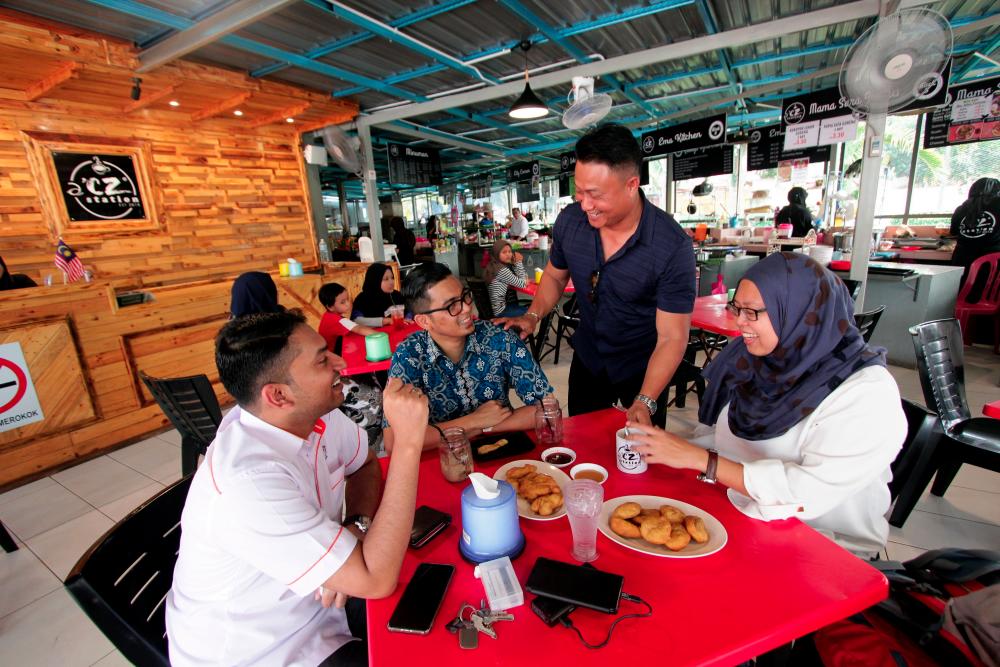 Owner of D’CZ Restaurant, Datuk Zairul Asmadi Mohd Sabies (standing), entertaining customers at his restaurant in Bandar Dara Chini. — Bernama