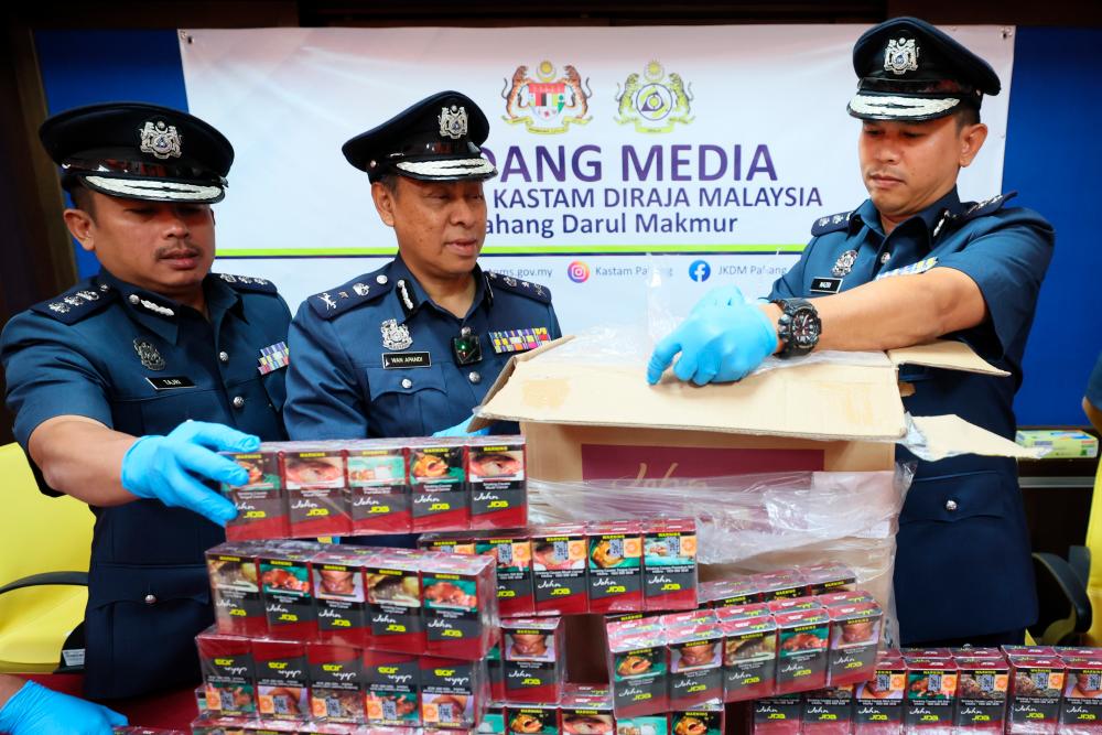 TEMERLOH, 17 Jan -- Pengarah Jabatan Kastam Diraja Malaysia (JKDM) Pahang, Wan Apandi Wan Hassan (tengah) menunjukkan sebahagian rokok yang dirampas pada sidang media berhubung kejayaan JKDM Pahang menumpaskan aktiviti sindiket penyeludupan rokok tidak berkastam bernilai RM2,169,280 di Pejabat JKDM Temerloh hari ini. fotoBERNAMA