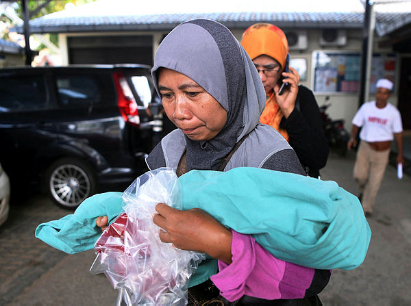 Grandmother Siti Aminah Rahmat, 42, carries the body of her 10-month-old dead granddaughter Nurul Afiqah Umaira Muhammad Hafiq from the forensic unit of the Tengku Ampuan Afzan Hospital on April 24, 2019. — Bernama
