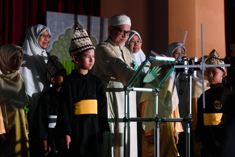 PAS president Datuk Seri Abdul Hadi Awang places his hands on the symbolic plaque of the 59th PAS Muslimat general annual assembly in Kuantan on June 15, 2019. - Bernama