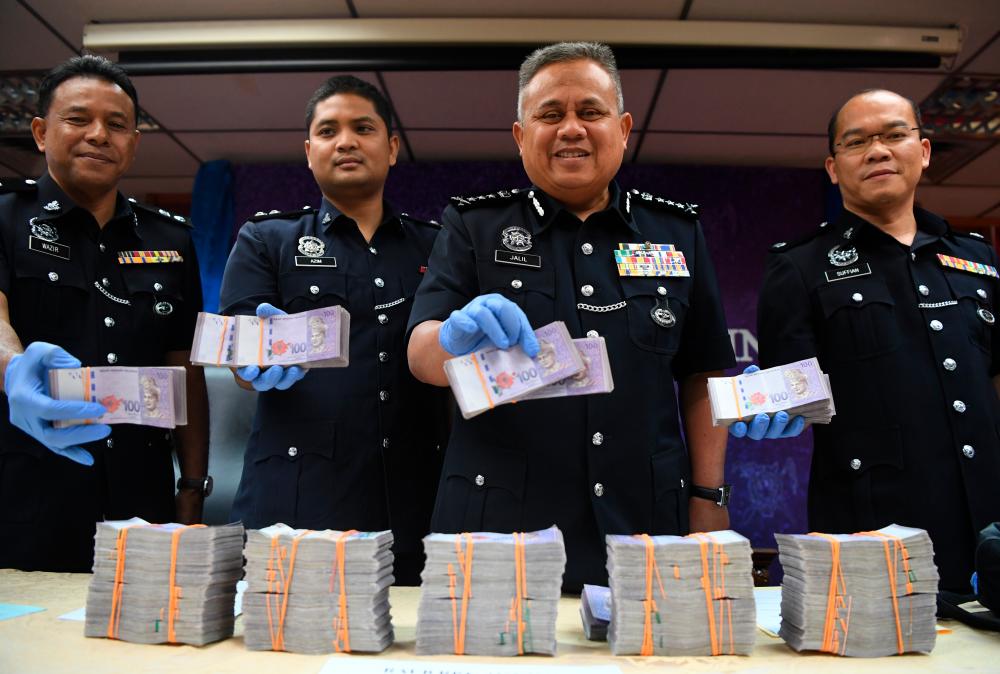 Pahang police chief Datuk Abd Jalil Hassan (2nd from R) along with other officers display the RM600,000 that was recovered after an attempted theft. - Bernama