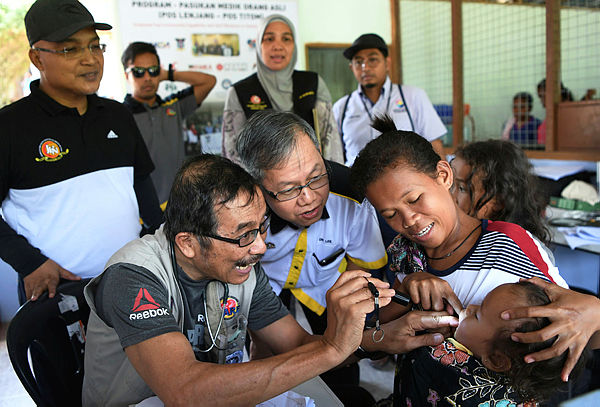 Deputy Health Minister Dr Lee Boon Chye (front, two from left), watching orang asli receive treatment during the opening of the Orang Asli Pos Medik Centre in Kampung Dayok, Pos Lenjang. — Bernama