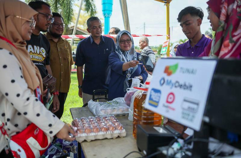 Pengarah Suruhanjaya Komunikasi dan Multimedia (MCMC) Negeri Pahang, Shahrizal Husin (empat dari kiri) melihat pengguna membuat pembayaran menggunakan kad debit pada Pelancaran Program Cashless @ NADI Jenderak Utara di Felde Jenderak Utara hari ini. - fotoBERNAMA