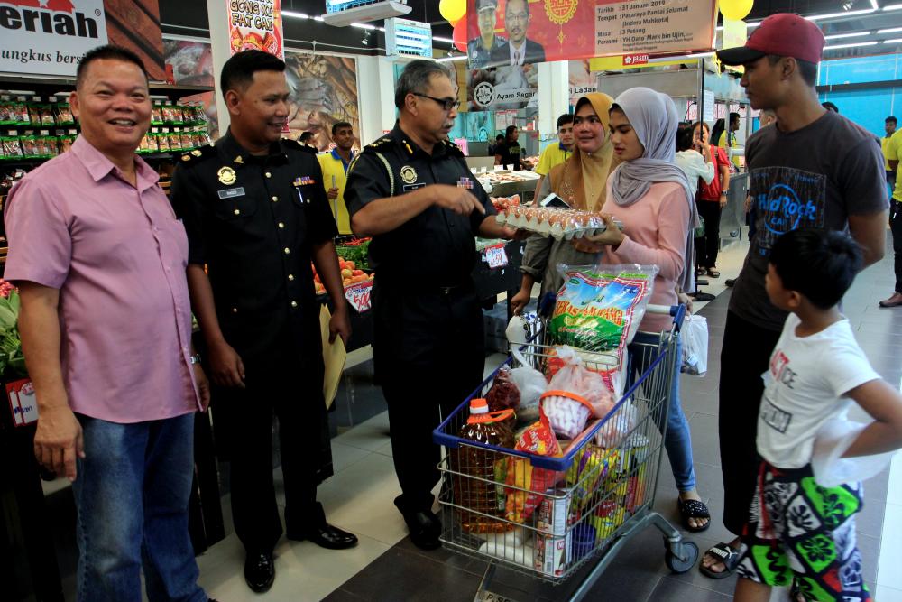 Deputy Director of the Ministry of Domestic Trade and Consumer Affairs (KPDNHEP) Pahang Alwi Abdul Hamid (3L) asks consumers about the price of goods purchased after the launch of the state-level Chinese New Year Spring Price Control Scheme at Pantai Selamat Supermarket, on Jan 31, 2019. — Bernama