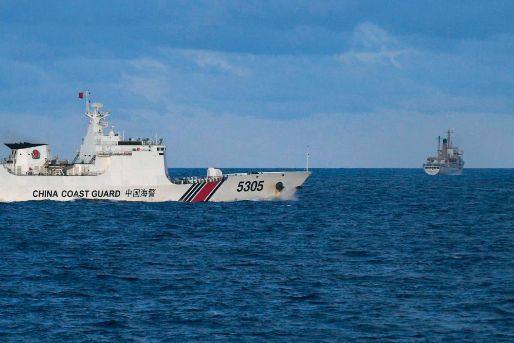A Chinese Coast Guard ship sails near a Philippine vessel (R) that was part of a convoy of civilian boats in the disputed South China Sea on December 10, 2023. - AFPPIX