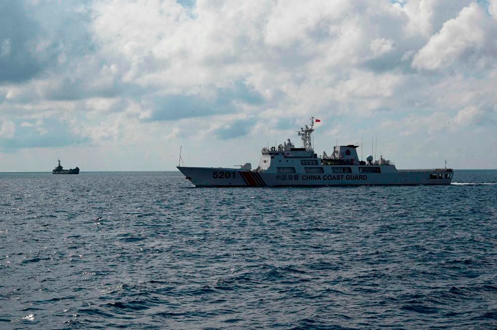 Chinese coast guard ship (R) patrolling near the grounded navy ship BRP Sierra Madre (L) where Philippine marines are stationed to assert Manila’s territorial claims in the disputed South China Sea. AFPPIX