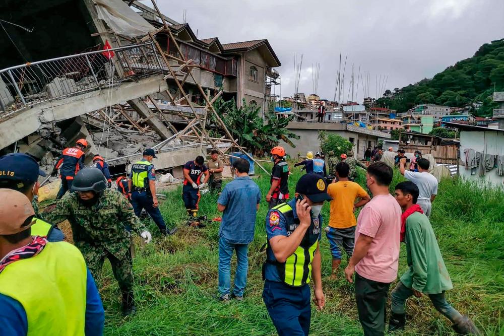 This handout photo taken from the Facebook page of La Trinidad Municipal Police Station shows a rescue team at the site of a collapsed building in La Trinidad, in the province of Benguet on July 27, 2022, after a 7.0-magnitude earthquake hit the northern Philippines. AFPPIX