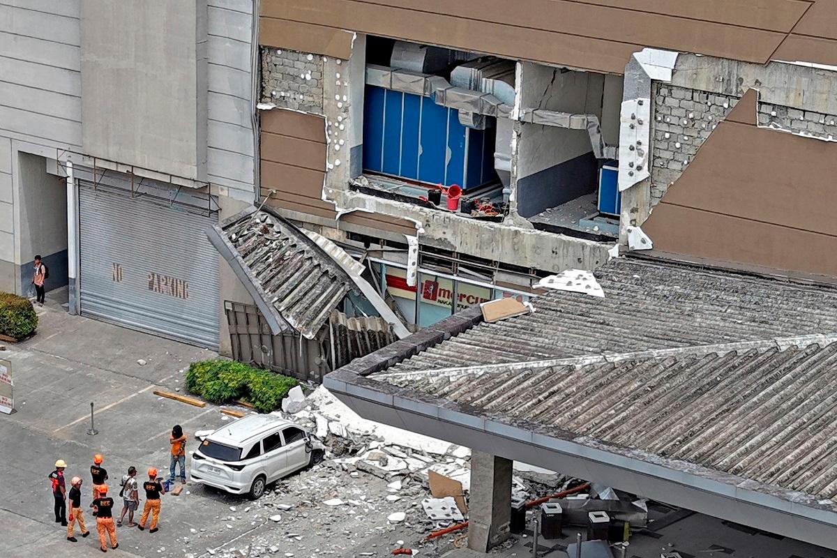 Authorities inspect a damaged wall and a car outside a mall in Butuan City, on the southern island of Mindanao on October 10, 2025, after a 7.4-magnitude earthquake struck off the southern Philippines. - Erwin MASCARINAS / AFP